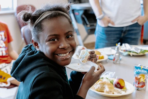 A young girl smiles while eating cake at the Open Door Mission.