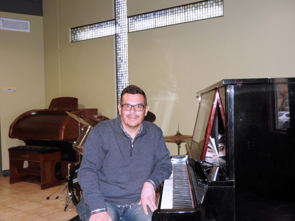 Johnny sitting next to a piano at the mission.
