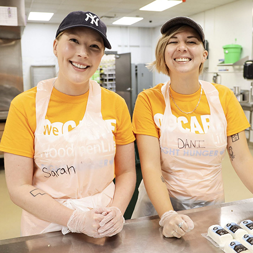 Two women wearing aprons volunteer at Open Door Mission to help.
